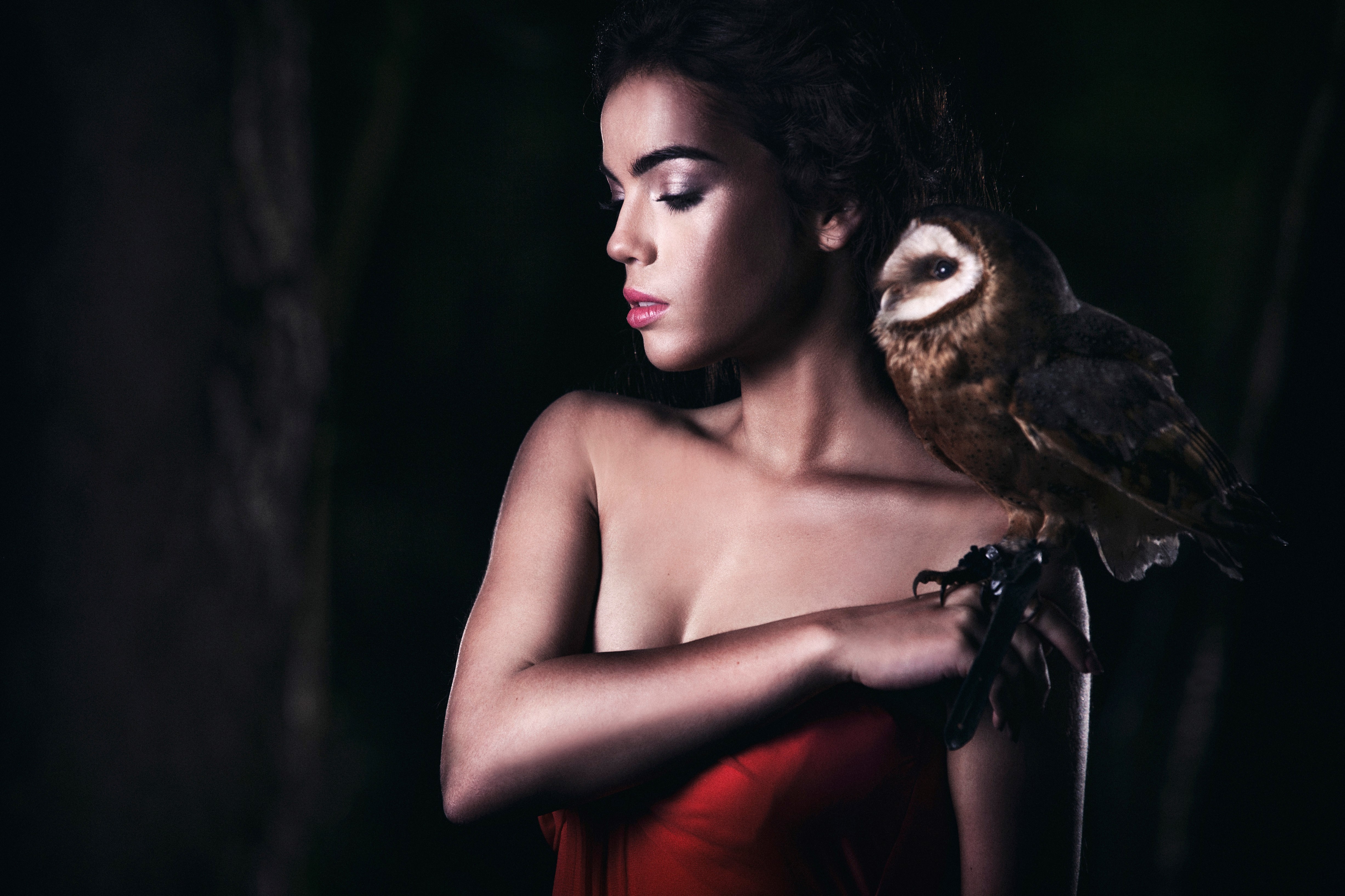 Portrait of a beautiful caucasian young woman posing with a barn owl in a forest.